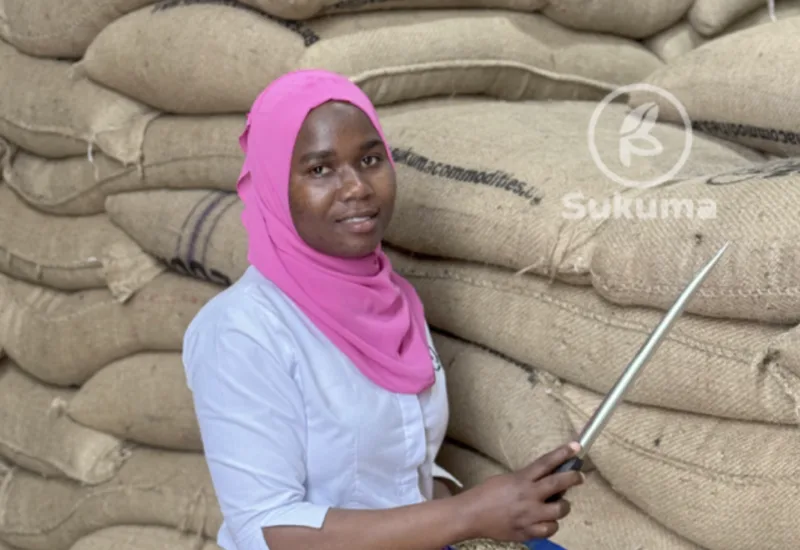 Sukuma team member beside stacked jute coffee sacks in store